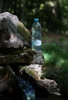 a bottle of water sitting on top of a rock