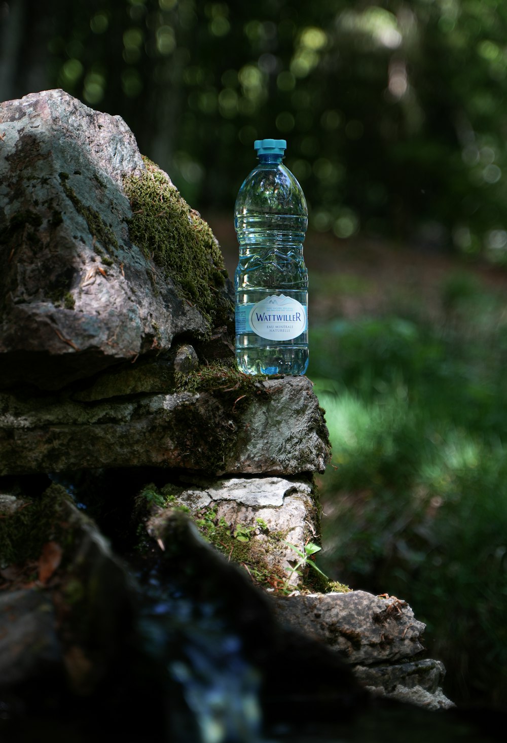 a bottle of water sitting on top of a rock