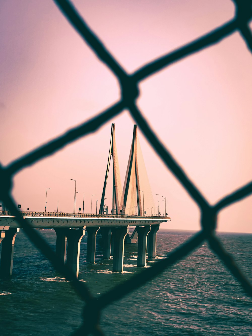 a view of a bridge from behind a chain link fence