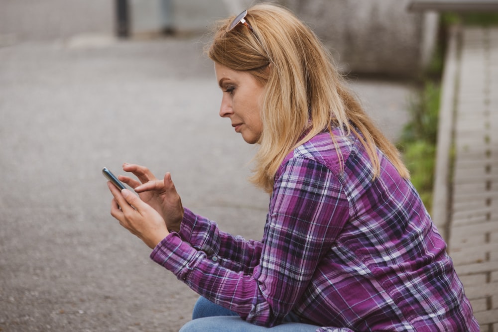 uma mulher sentada no chão olhando para seu telefone celular