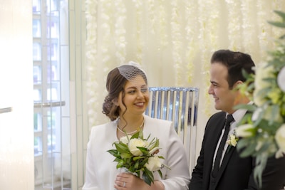 A bride and groom smiling as they discuss wedding plans with their coordinator in a cozy office.