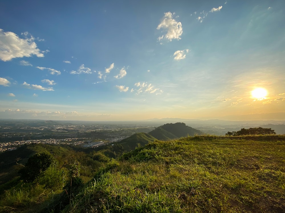 the sun is setting over a grassy hill