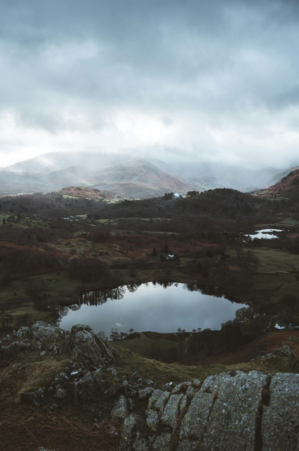 a lake surrounded by mountains under a cloudy sky