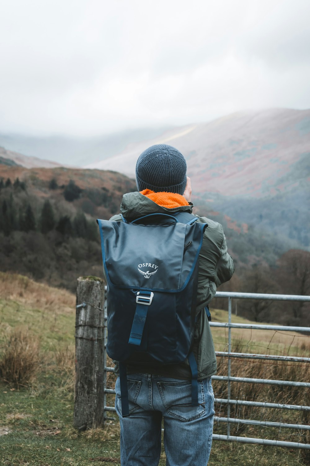 eine Person mit einem Rucksack, die über einen Zaun blickt