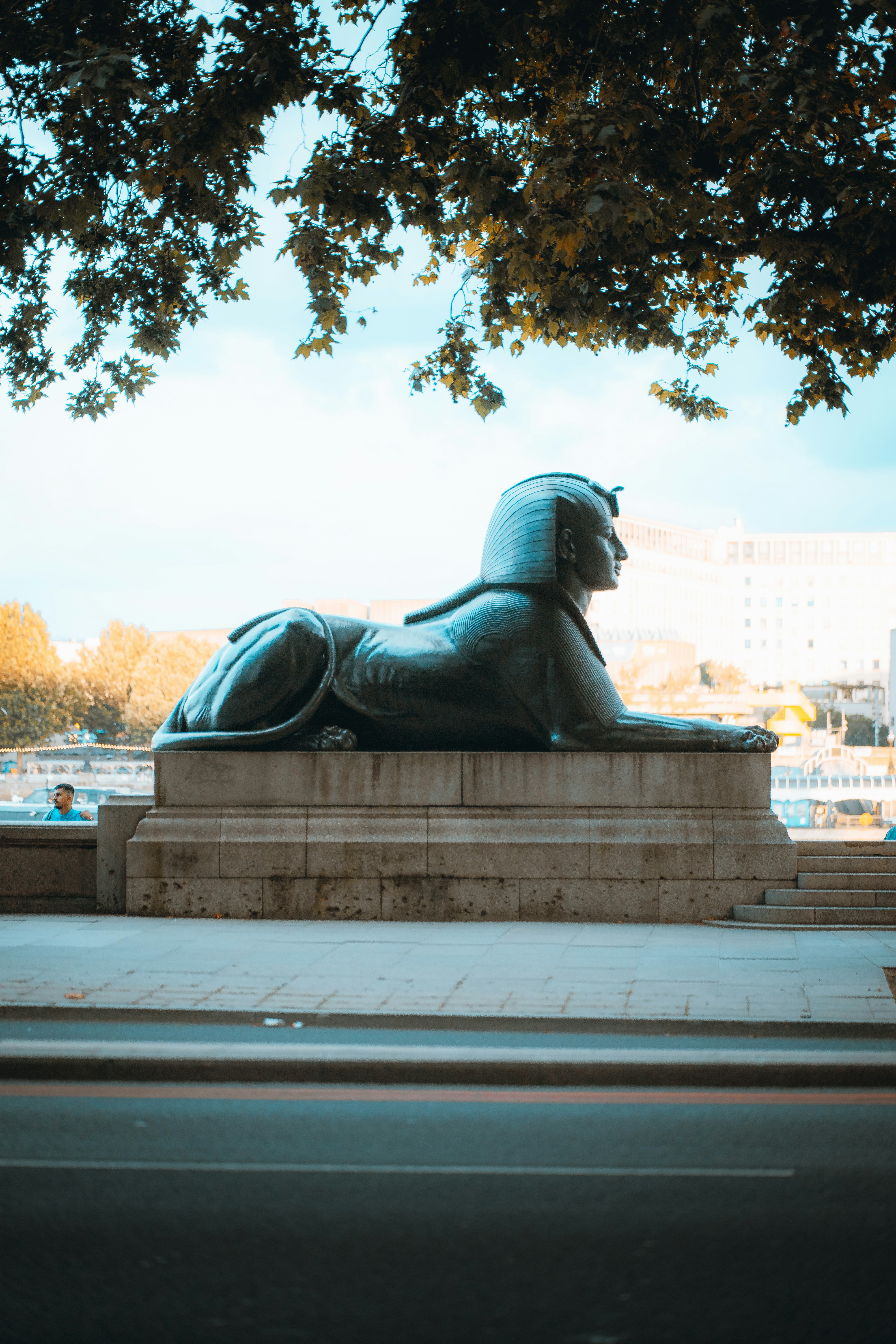 a statue of a lion on a pedestal under a tree