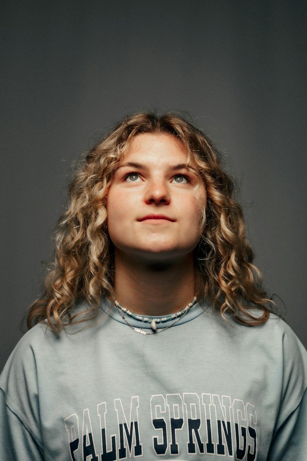 a woman with curly hair wearing a gray shirt