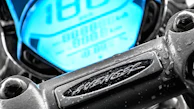 Close-up of a motorcycle dashboard glowing with red and white lights in dark mode