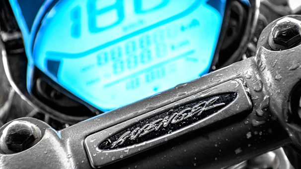 Close-up of a sleek motorcycle dashboard illuminated in neon green at dusk.