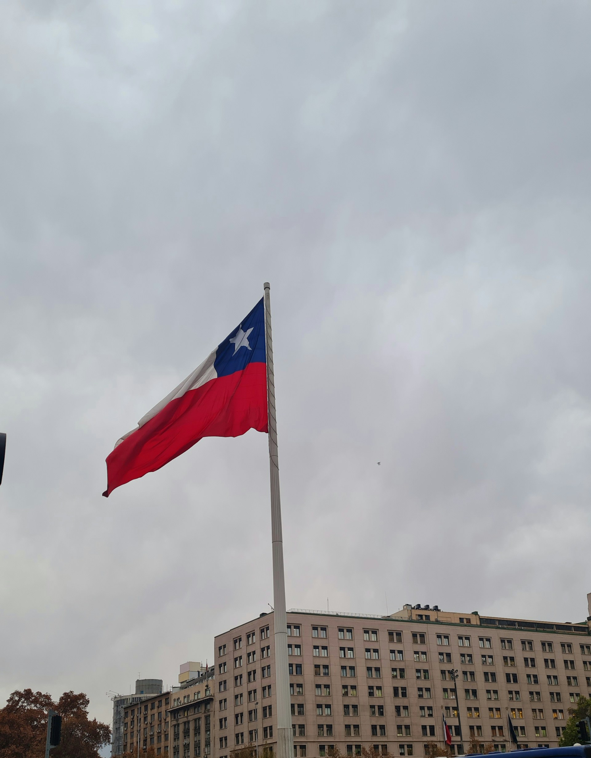 a flag flying in the wind next to a tall building