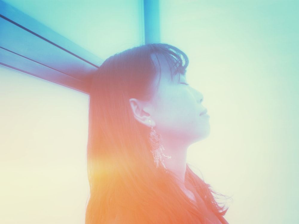 a woman with long hair looking out a window