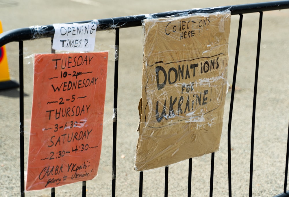 a couple of signs are hanging on a fence