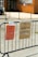 Two signs are attached to a black metal fence. The first sign on the left is orange and details opening times on Tuesday, Wednesday, Thursday, and Saturday. The second sign on the right is cardboard, labeled for donations to Ukraine. The background features a brick building and a parked car.