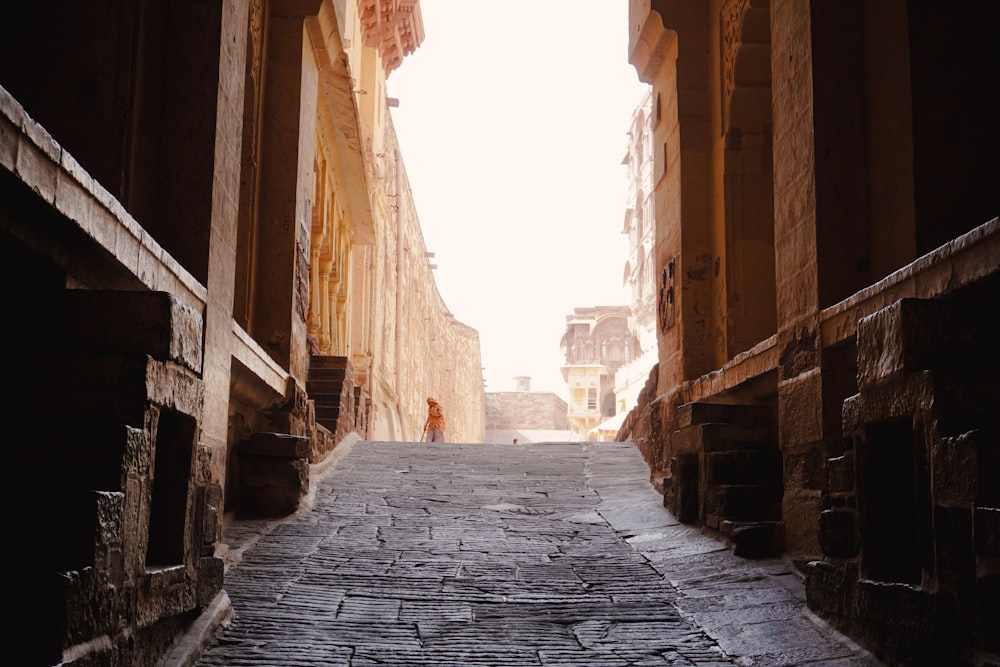 a narrow alley way with a person walking down it