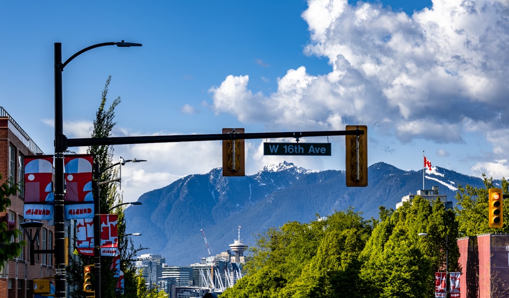 a street light with a street sign in front of a mountain
