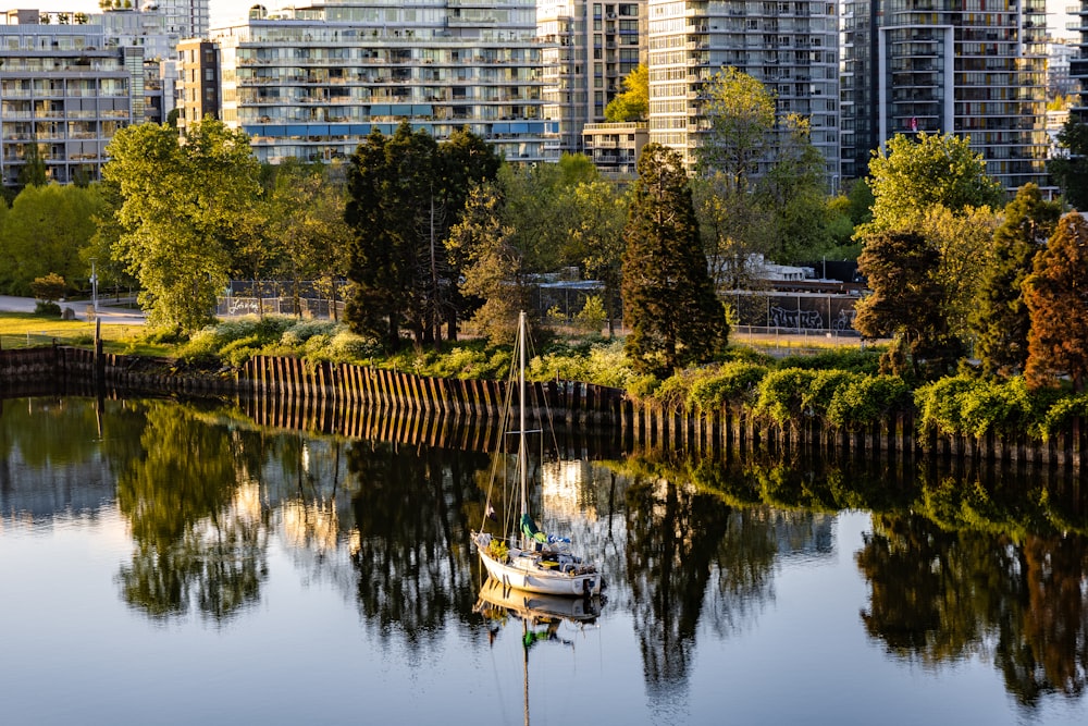 a small boat floating on top of a lake next to tall buildings