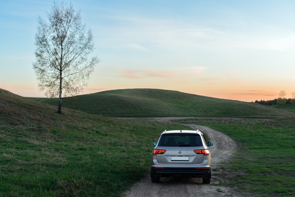 a car parked on a dirt road near a tree