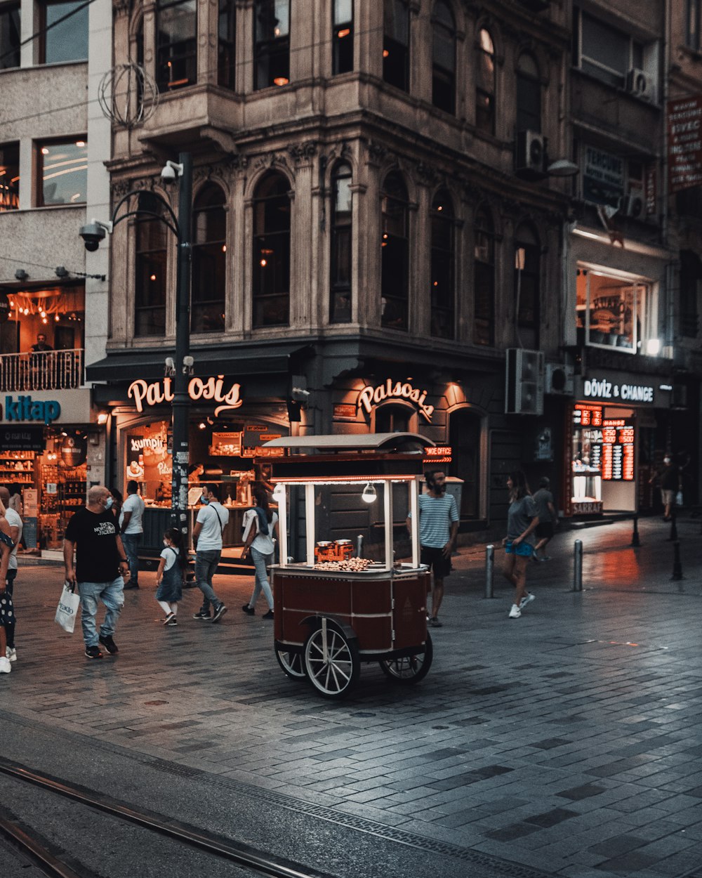 a street scene with people walking and a horse drawn cart