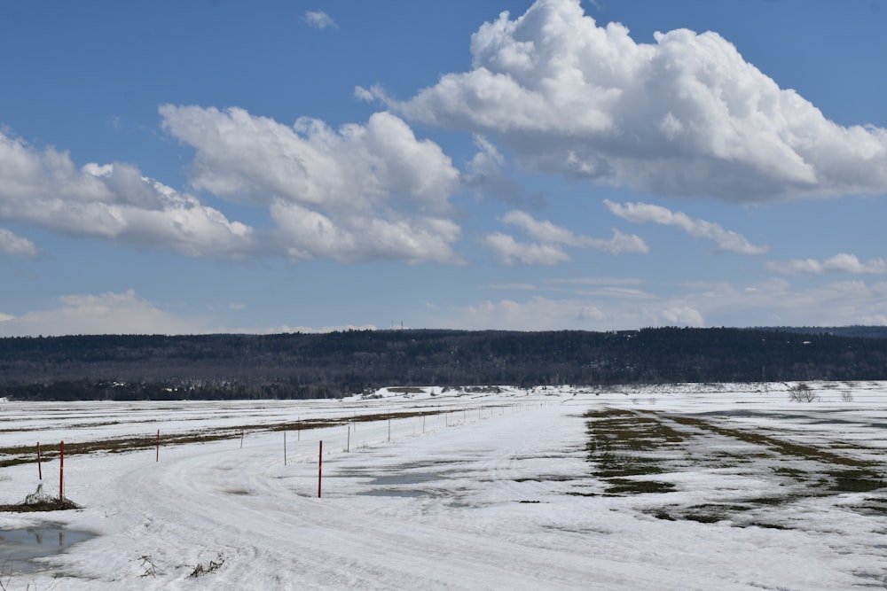 a snow covered field with a road in the middle of it