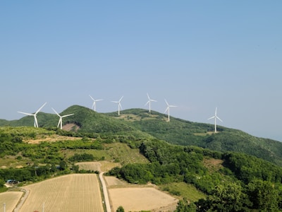 A renewable energy wind turbine farm stretching across green hills.