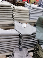Stacks of folded casual wear with price tags visible in a wholesale setting.