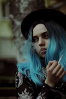 a woman with blue hair smoking a cigarette