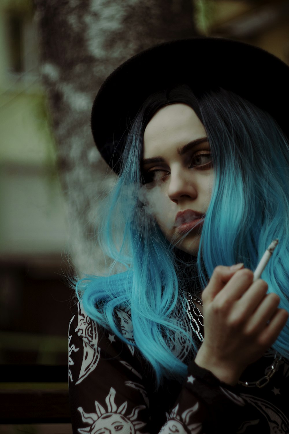 a woman with blue hair smoking a cigarette
