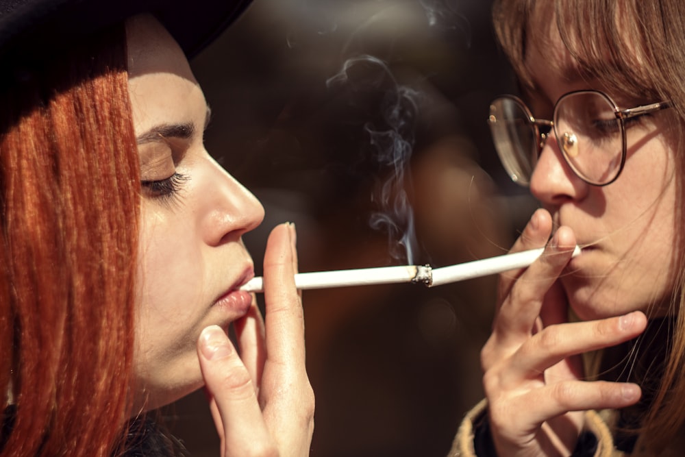 Dos mujeres fumando un cigarrillo y mirándose