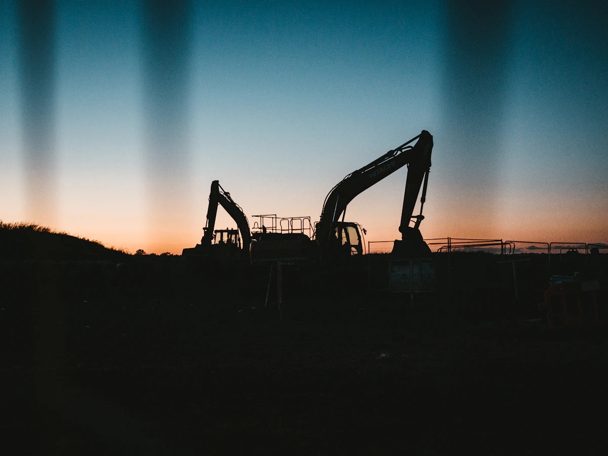 Engin de chantier en silhouette au coucher du soleil sur un site de travaux