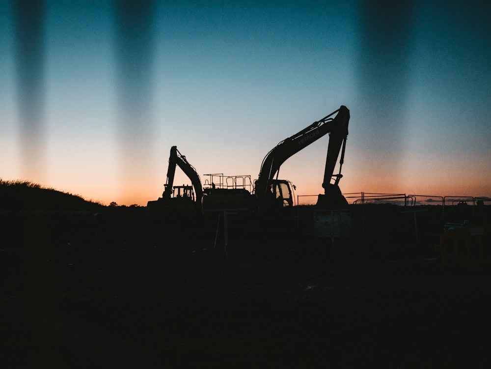 an excavator is silhouetted against a sunset