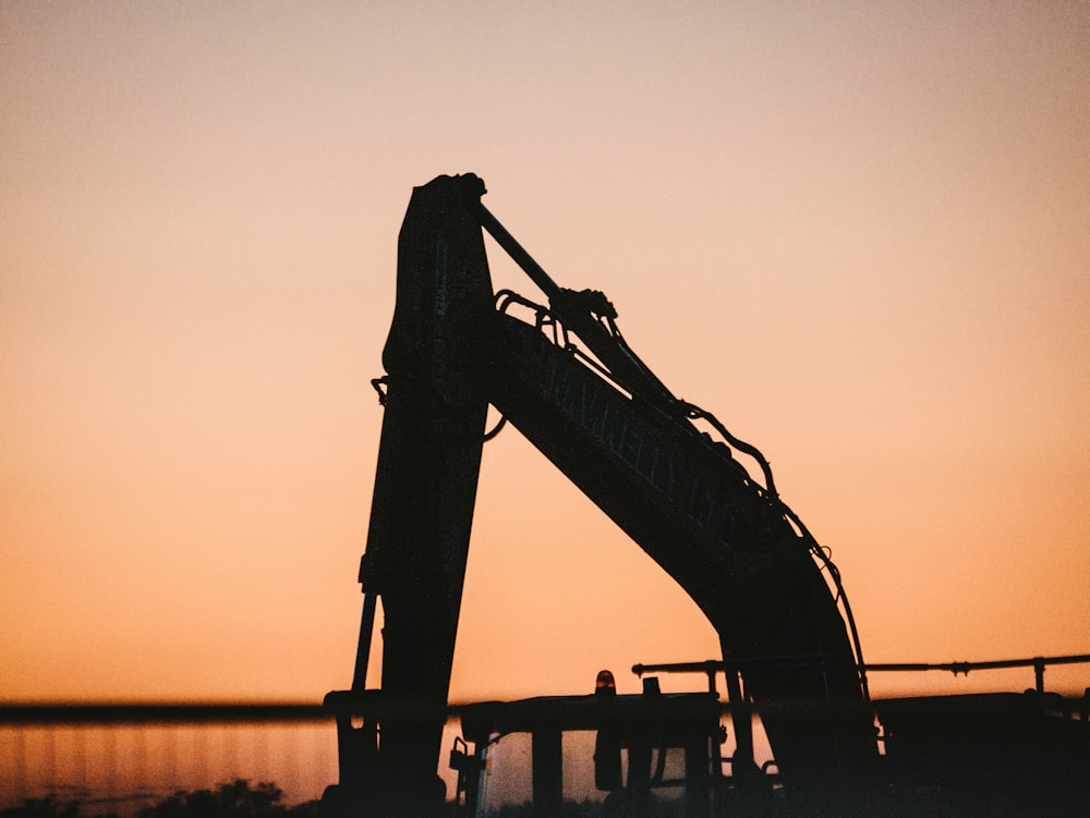 a crane is silhouetted against a sunset sky