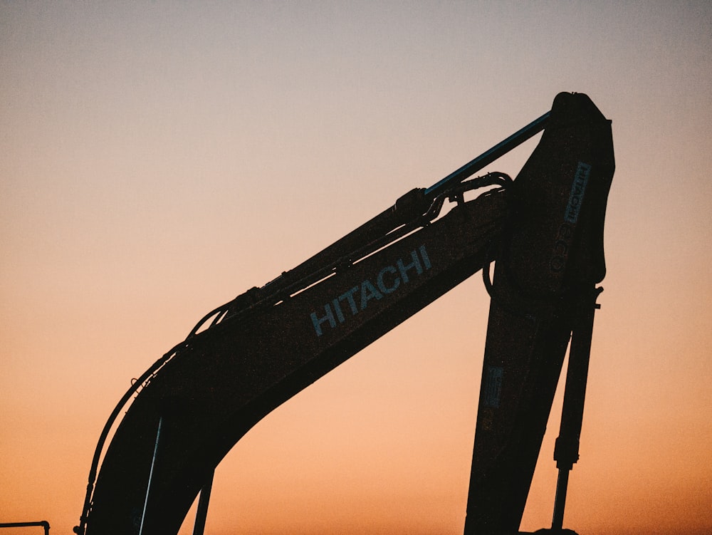 a silhouette of an excavator against a sunset sky