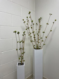 Tall, elegant fiberglass vases holding lush greenery, adding a modern touch to a garden corner.