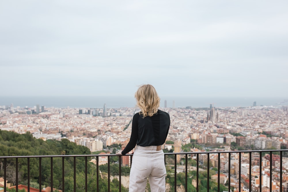 a woman standing on a balcony overlooking a city