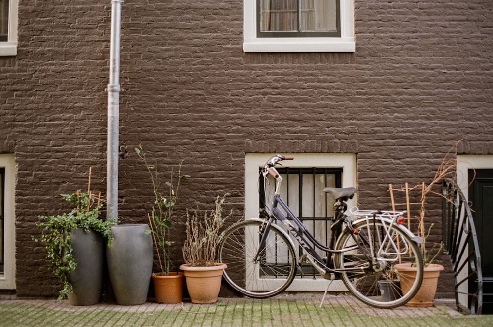 a bicycle parked next to a building with potted plants