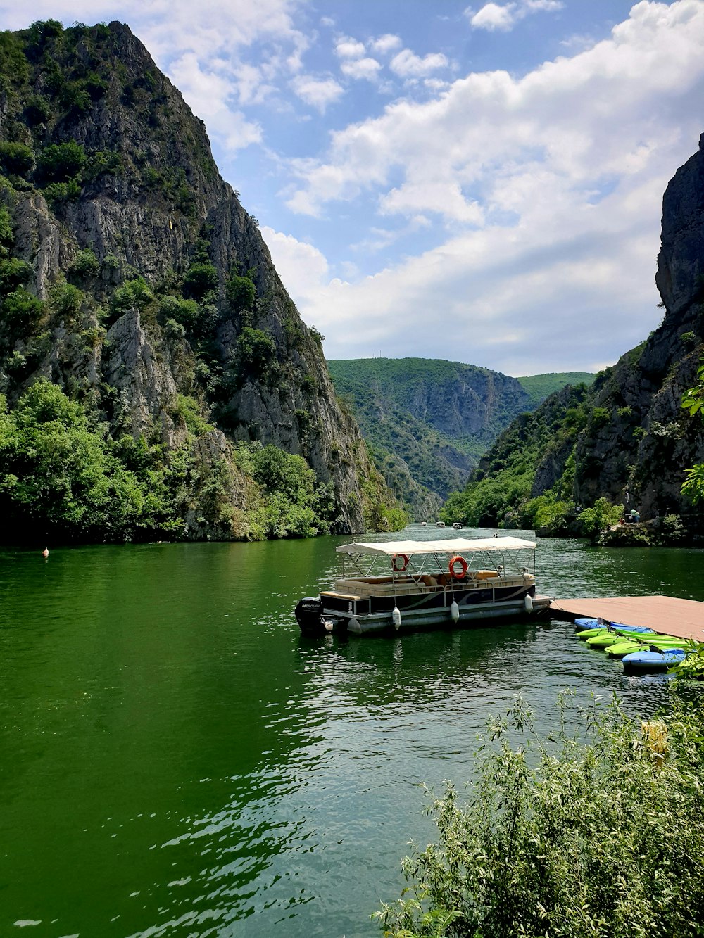 a boat floating on top of a river next to a lush green hillside