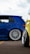 A close-up view of two modified cars showcasing custom wheels and lowered suspensions, parked on an asphalt surface. The blue car has a sleek design with a polished metal rim while a portion of a yellow car is visible in the foreground.