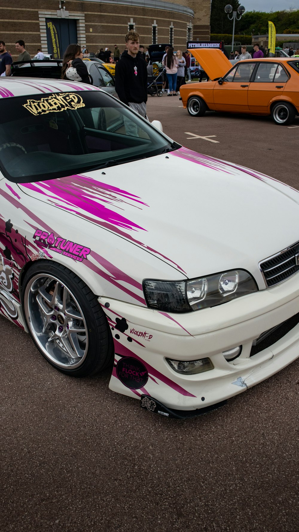 a white car with a pink and purple paint job parked in a parking lot