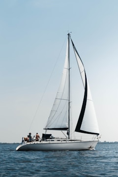 Sleek sailing yacht cutting through calm blue sea under clear skies.
