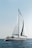 A serene view of a yacht sailing on calm blue waters under a clear sky.
