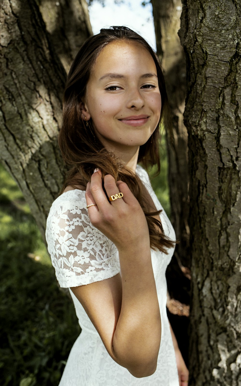 a woman standing next to a tree in a forest