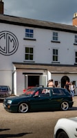 A group of happy students standing next to their cars in front of the mb-drive office in Thun.