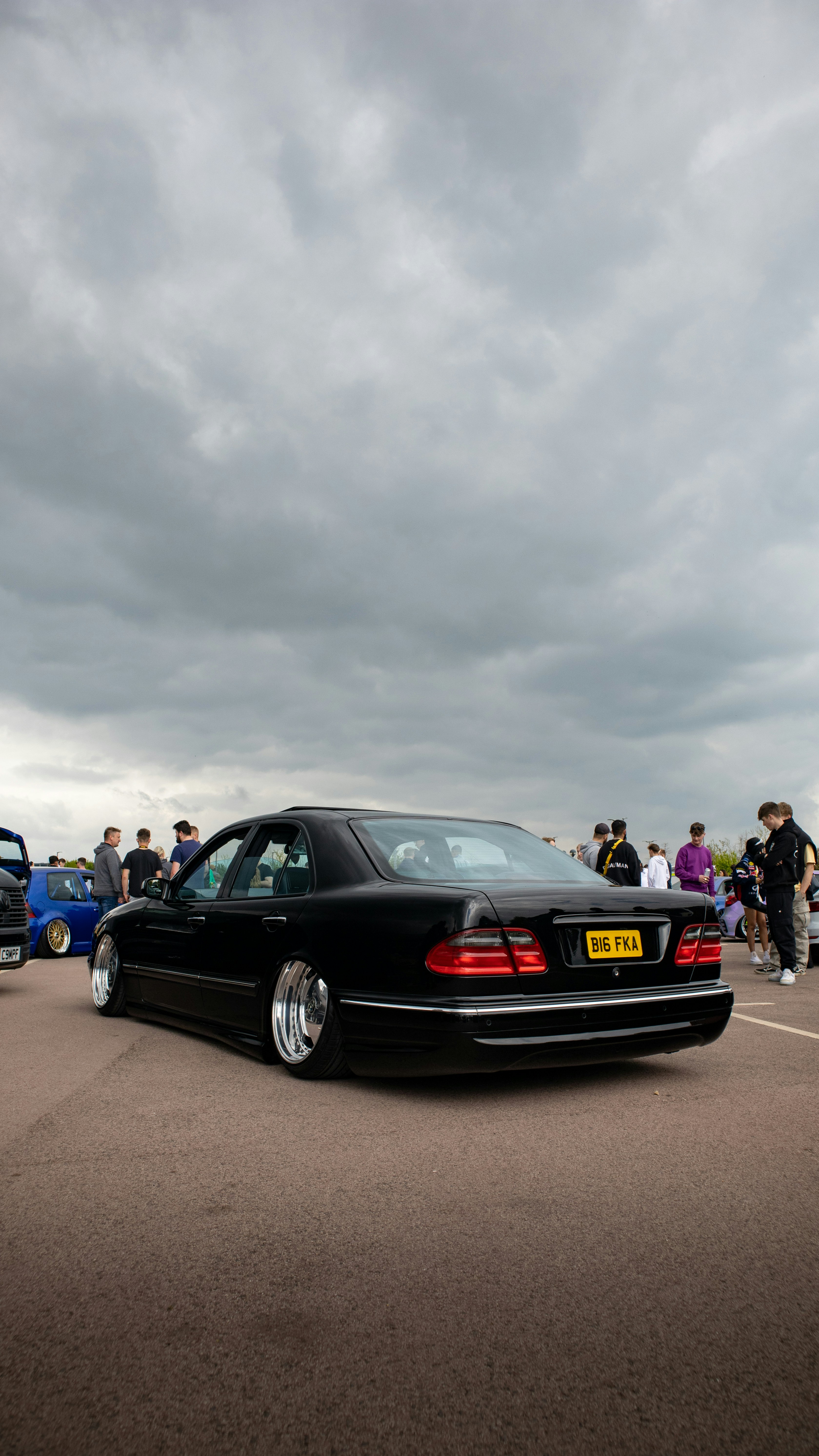 a black car parked in a parking lot next to other cars