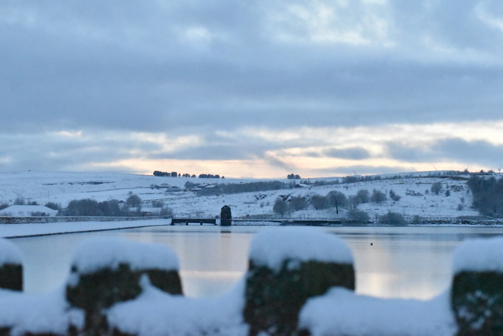 a fence with snow on it and a lake in the background