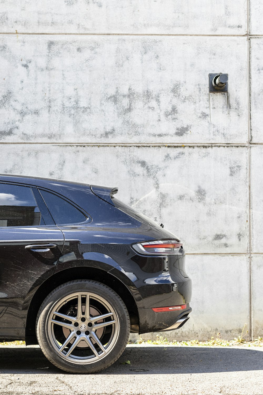 a black car parked in front of a concrete wall