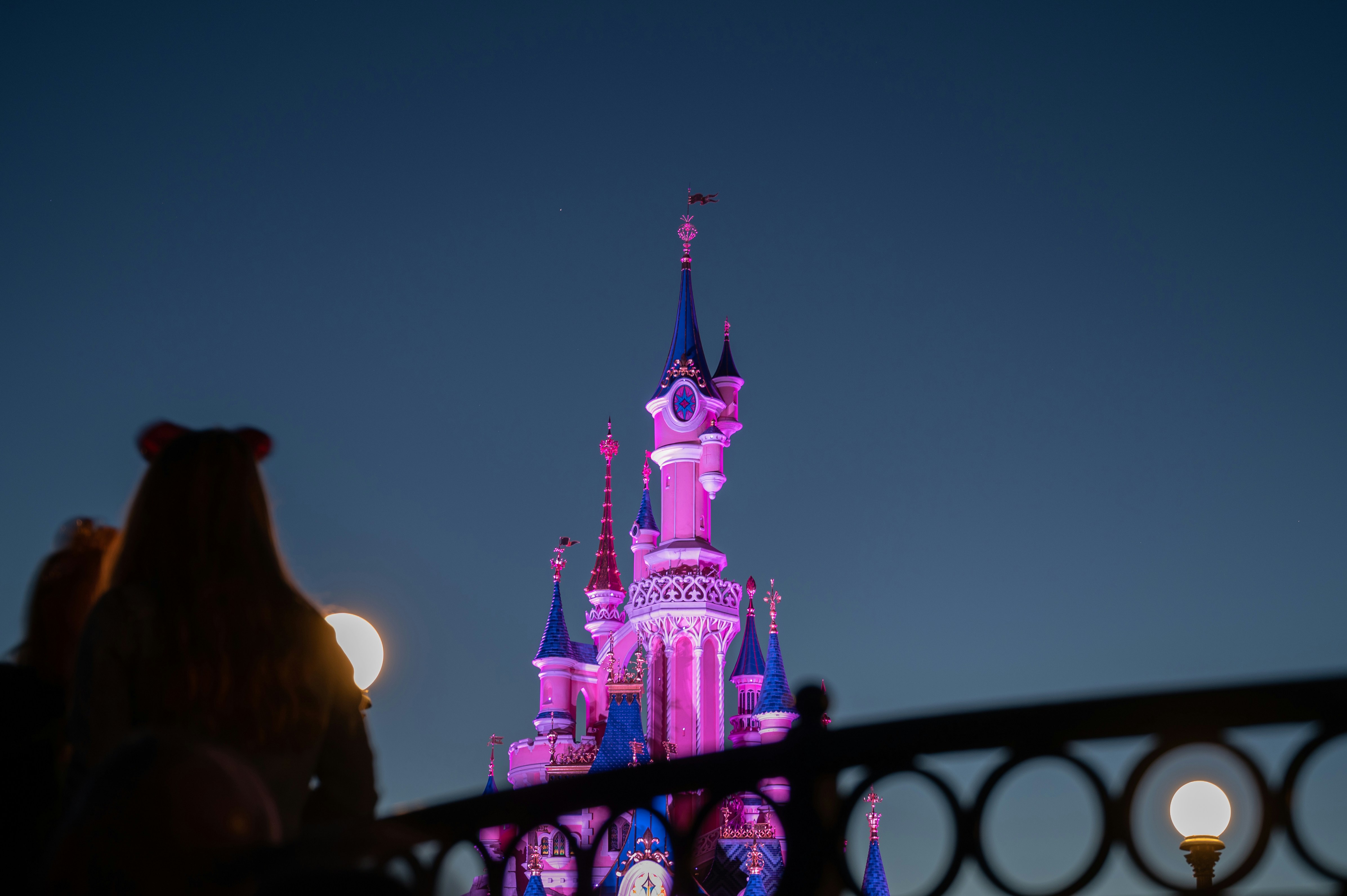 a pink castle lit up at night with a sky background