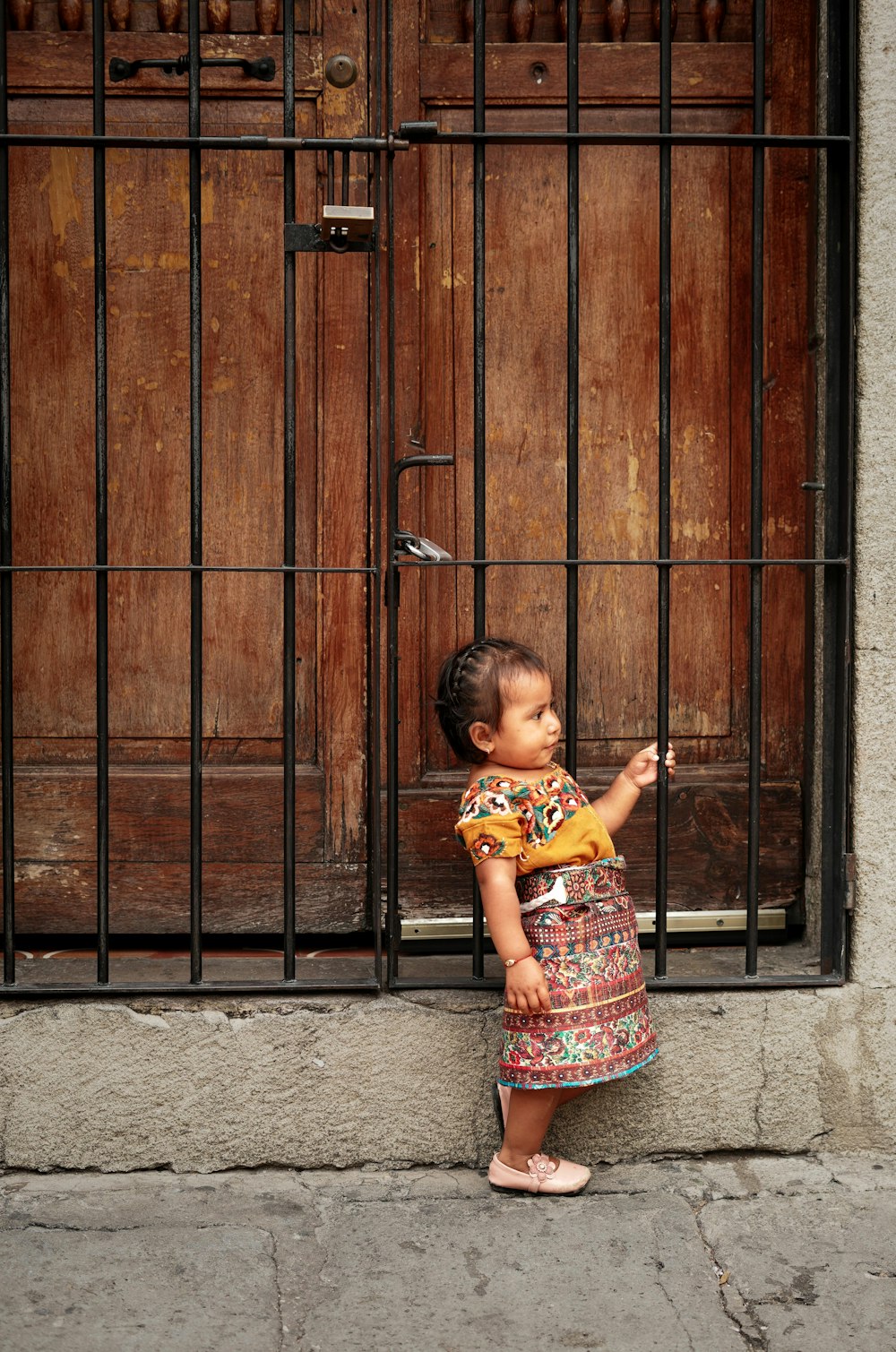 uma menina em pé na frente de uma porta de madeira