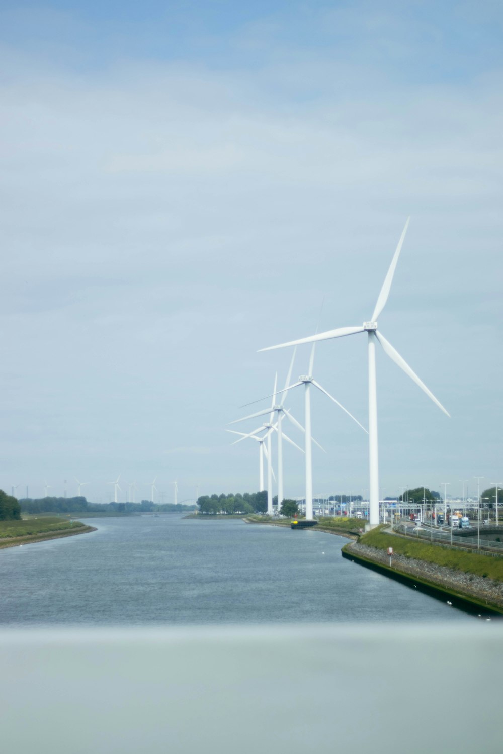 a row of wind turbines next to a body of water