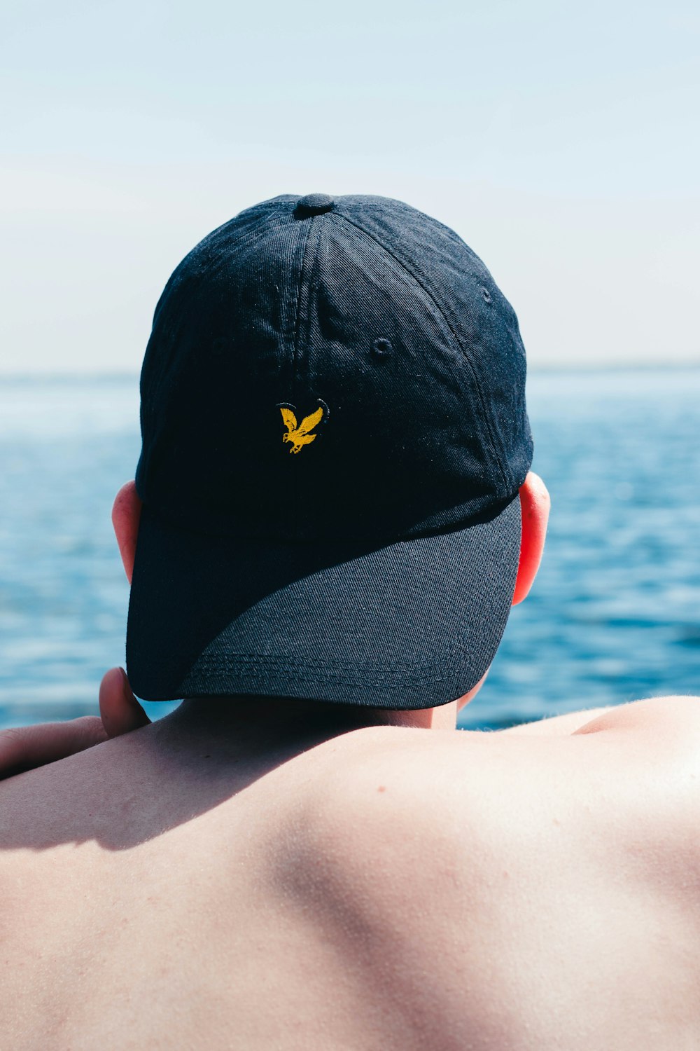 a man wearing a hat looking out at the ocean
