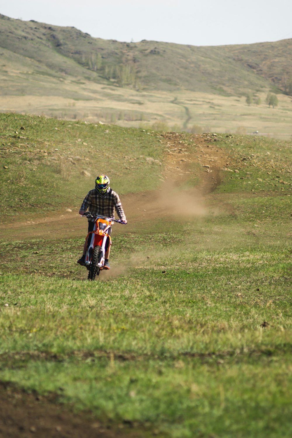 a man riding a dirt bike on top of a lush green field