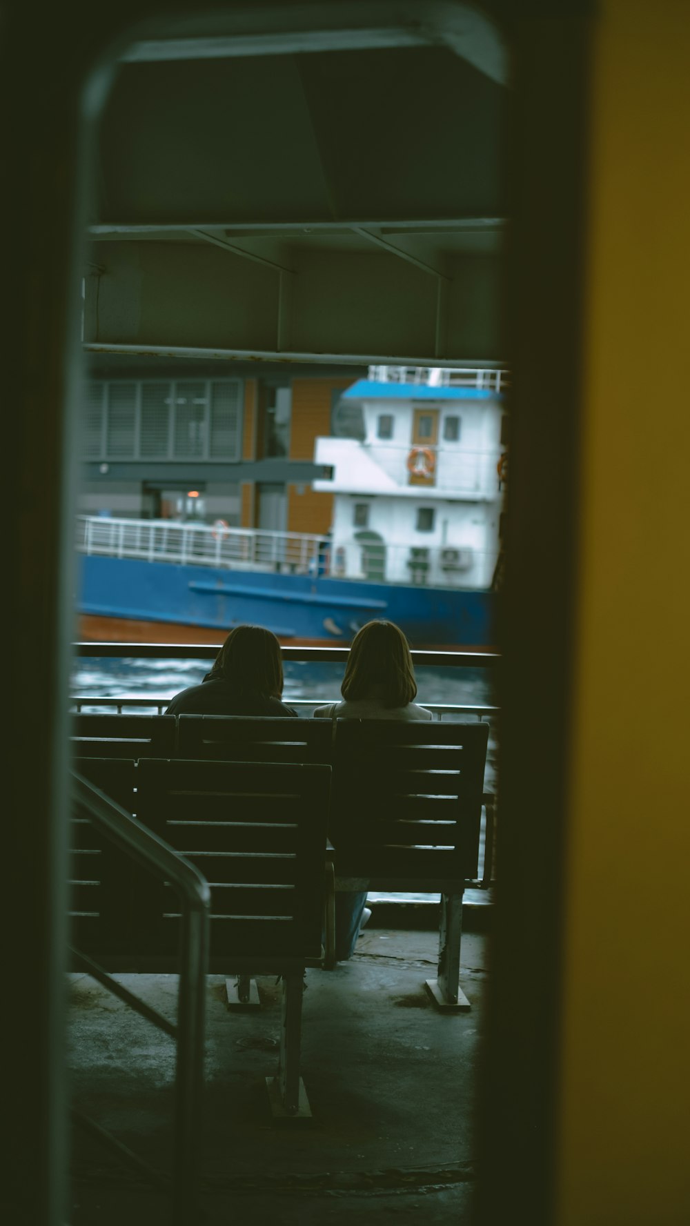 two people sitting on a bench in a train station